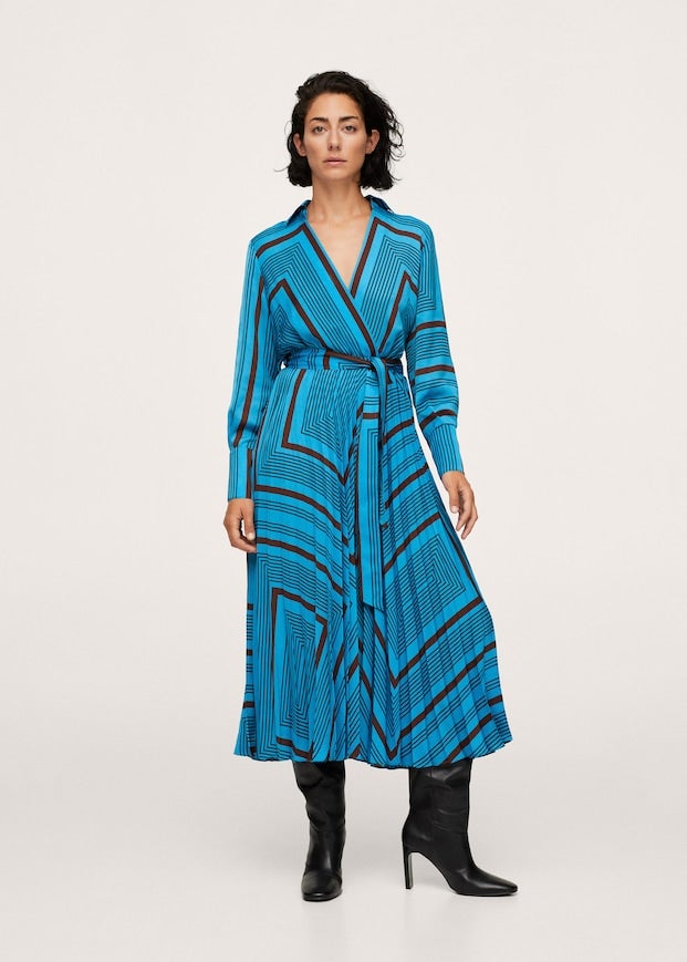 Este precioso vestido azul con estampado geométrico en tonos marrones es de Mango y está confeccionado en tejido fluido satinado. De diseño midi acampanado, viene con escote de pico cruzado, mangas largas con puños abotonados y lazo ajustable en la cintura a tono. Tiene la falda plisada, cuesta 59,99 euros y está disponible entre las tallas XXS y XL. 
