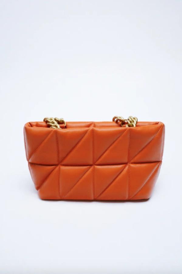 Diseño city para este bolso de Zara que está disponible en verde, negro y naranja caldera. Con cuerpo acolchado y asas de hombro con cadena gruesa, tiene cierre mediante cremallera y cuesta 35,95 euros. 