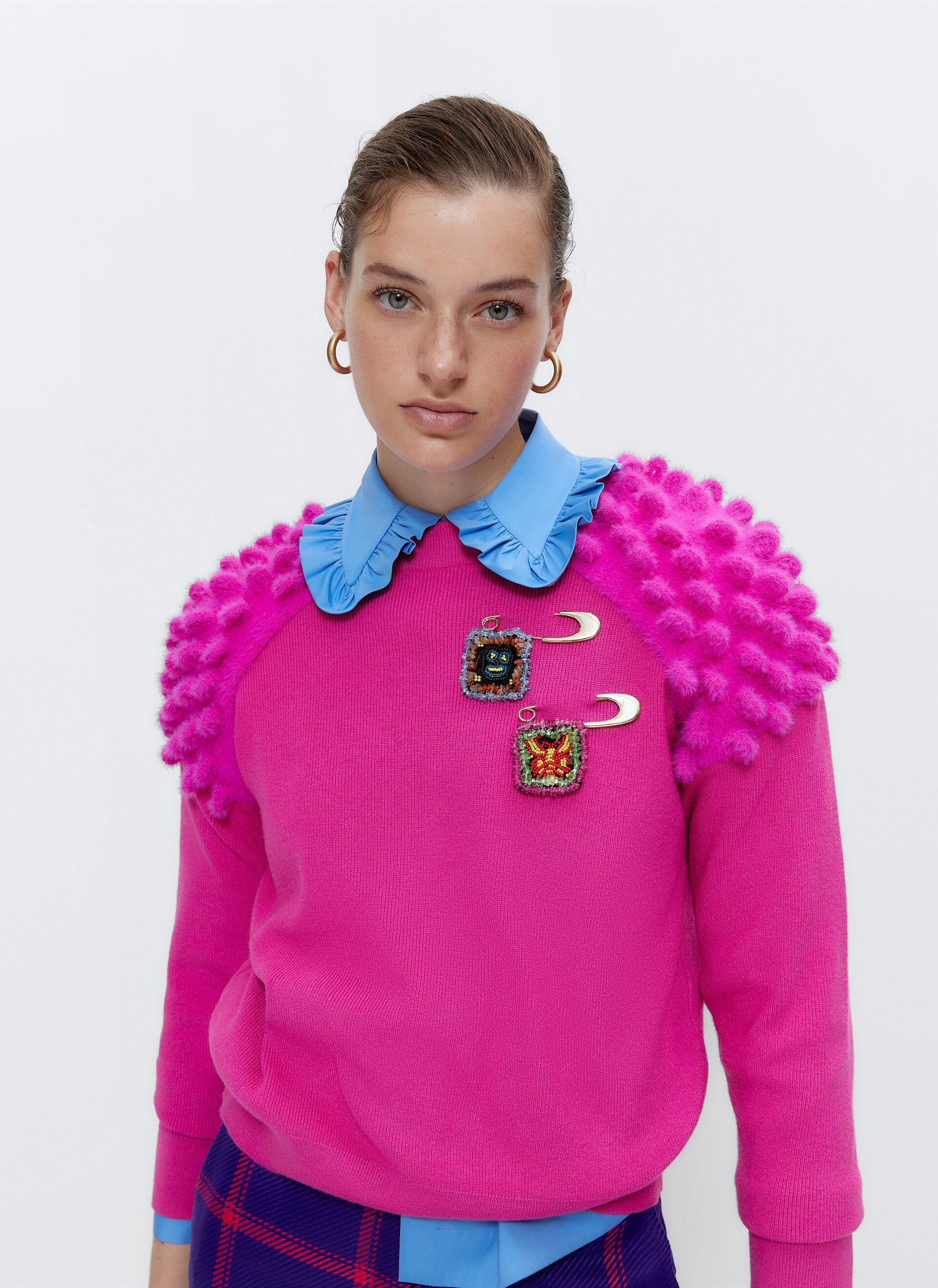 Este llaamtivo jersey fucsia con detalles de inspiración goyesca cuesta 69 euros, y los broches, 39 euros.
