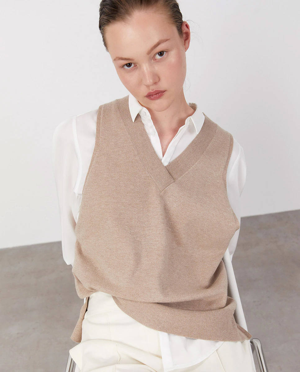 ¿Buscas un chaleco sencillo y versátil? Entonces deberías hacerte con este de Sfera en color camel con el cuello en forma de pico. Tiene un precio de 15,99 €.