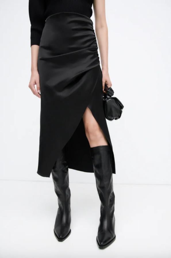 Tejido satinado en color negro para esta falda de Zara con frunces laterales que terminan en abertura. Con un precio de 29,95 euros, está disponible entre las tallas XS y XL. 