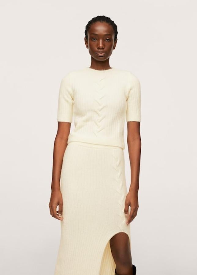Este jersey de punto en color crudo y diseño cropped de canalé es de Mango y viene con cuello redondo y mangas cortas. Con detalle trenzado en la parte central, cuesta 29,99 euros y está disponible entre las tallas XS y XL. 