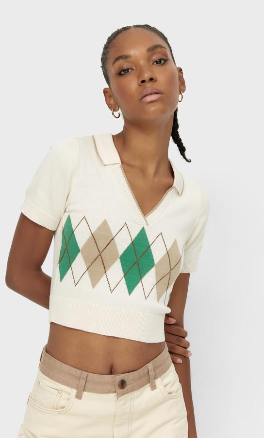 Diseño cropped para este jersey de Stradivarius con estampado de cuadros en tonos verdes, beige y marrón que viene con escote de pico, cuello polo y mangas cortas. Con terminaciones en rib, cuesta 15,99 euros y está disponible entre las tallas XS y XL. 