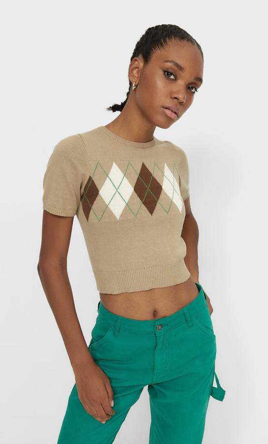 Con cuello redondo y diseño cropped, este jersey cropped en color terracota es de Stradivarius y viene con estampado de rombos en tonos marrones, crudo y verde. Tiene terminaciones en rib, cuesta 17,99 euros y está disponible entre las tallas XS y XL.