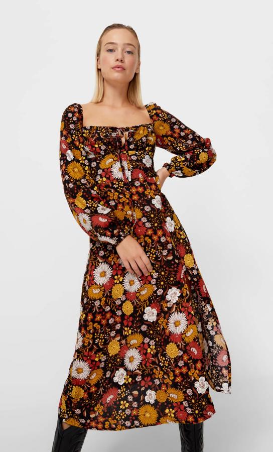 Con estampado floral en tonos marrones, este vestido midi con escote recto y detalle de atado en el cuello cuenta con manga larga abullonada y tiene un precio de 25,99 euros. Es de Stradivarius.
