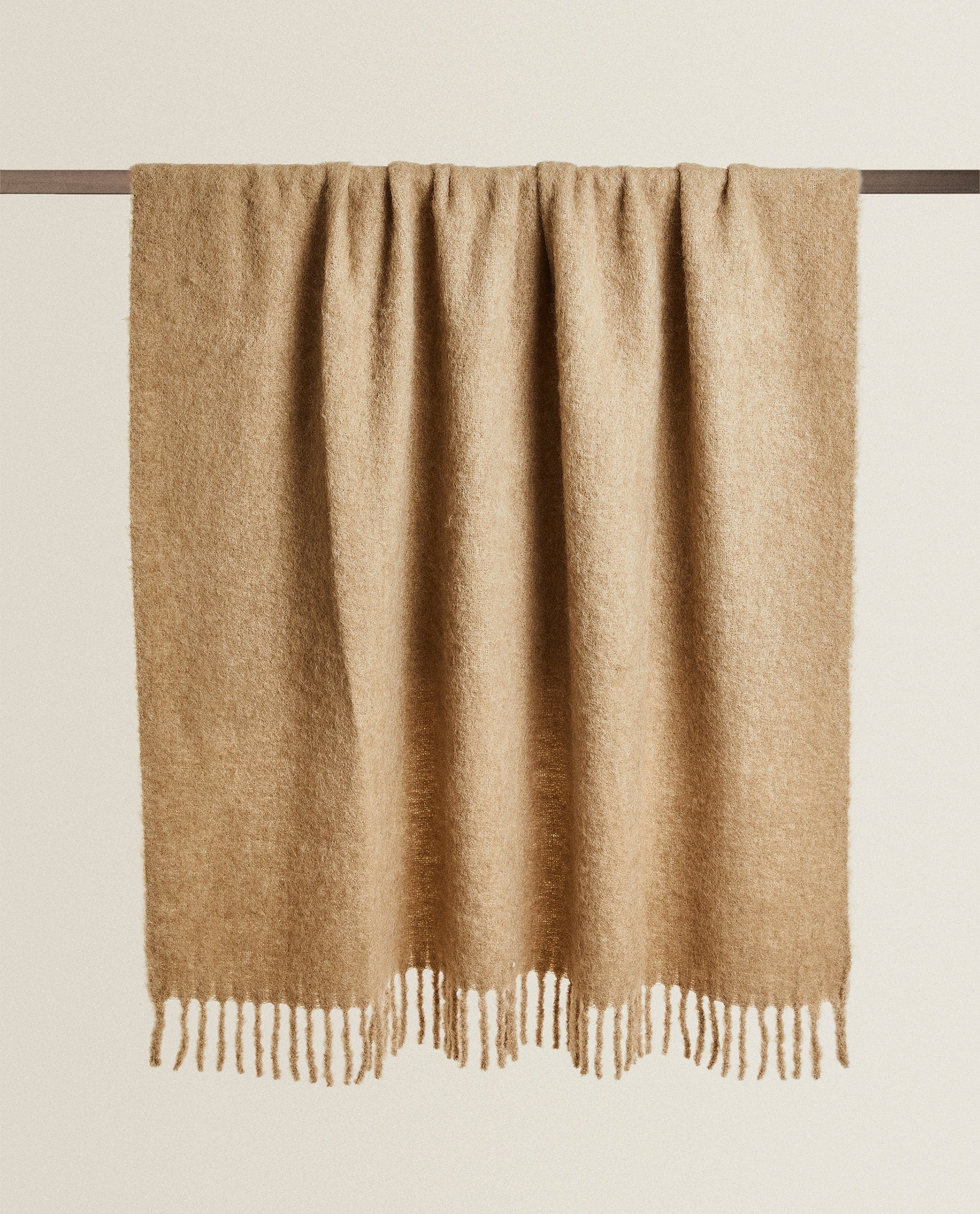 No podemos imaginar un plan mejor para los primeros días de frío que una buena sesión de pelis o series en el sofá arropadas con una manta tan confortable como esta de lana cardada de Zara Home (99 euros).