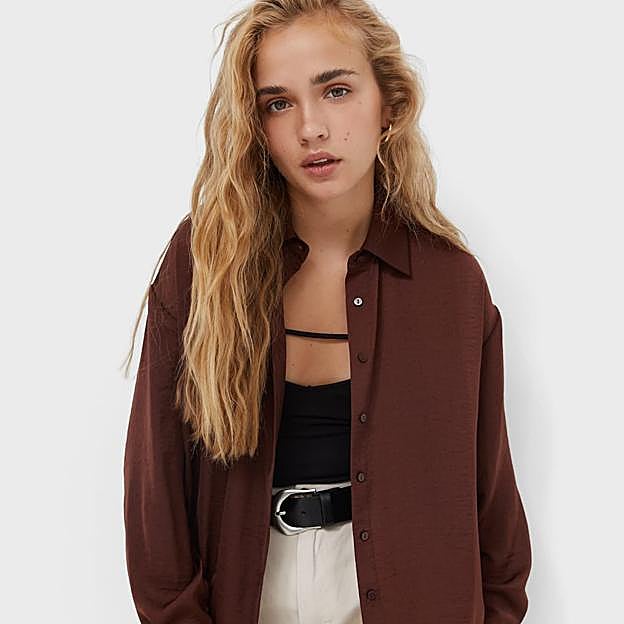 Imagen principal - La camisa de satén marrón que cuesta menos de 20 euros y rejuvenece a los 50 es el comodín que soluciona todos tus looks de entretiempo