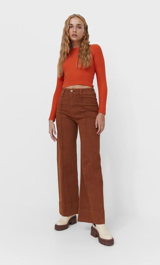 De cuello redondo y mangas largas, esta camiseta de diseño cropped en color naranja es de Stradivarius podemos encontrarla entre las tallas XS y XL por 9,99 euros. 