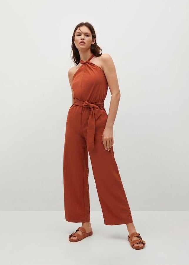 Confeccionado en tejido fluido, este mono naranja de Mango de diseño recto y cuello halter viene con cintura elástica con lazo ajustable a tono y dos bolsillos laterales. Cuesta 49,99 euros.