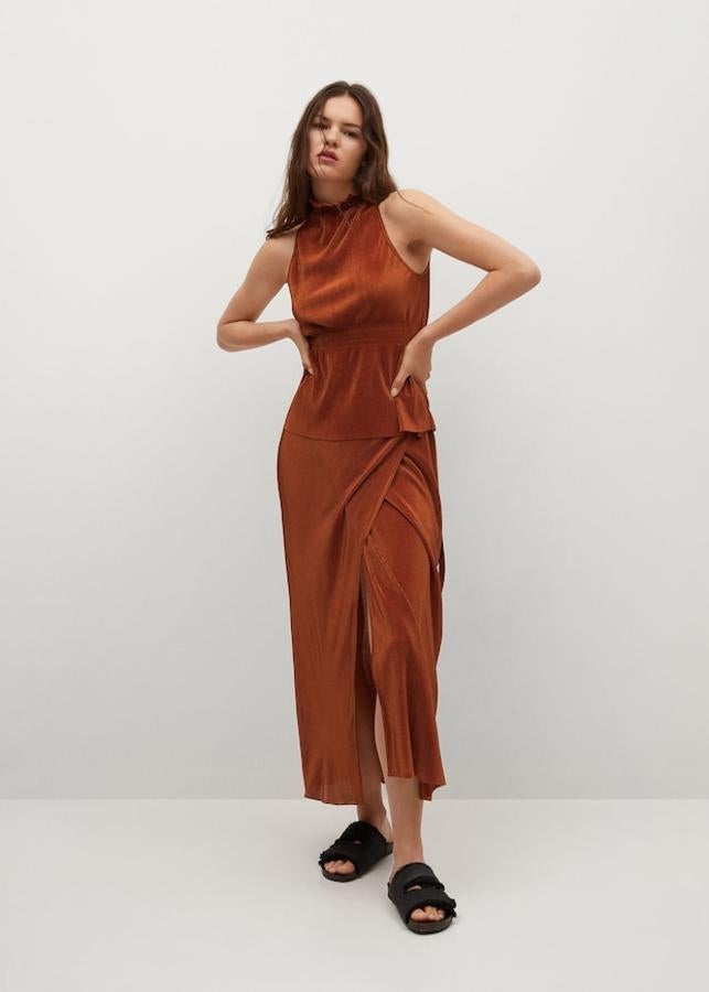 A juego con la falda, Mango ha lanzado este top plisado en tejido satinado y color naranja tostado. Tiene cuello halter y detalles elásticos en la cintura, es de diseño recto y viene sin mangas. Con un precio de 19,99 euros, podemos encontrarla en las tallas S, M y L. 