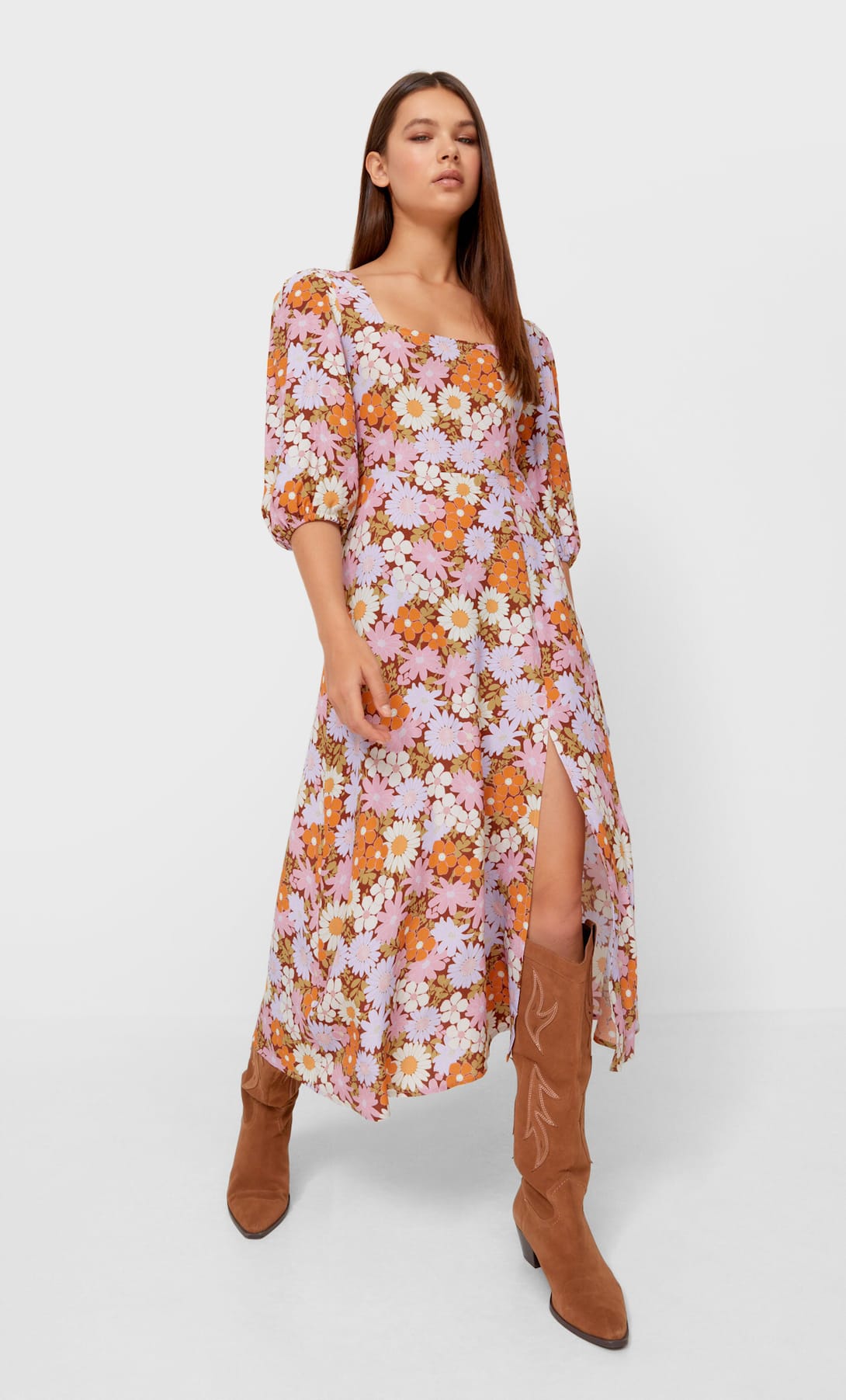 Romántico y muy naive, este vestido midi con abertura en la falda y estampado de flores de Stradivarius (25.99 euros) tiene en las botas cowboy (69.99 euros) su complemento perfecto.