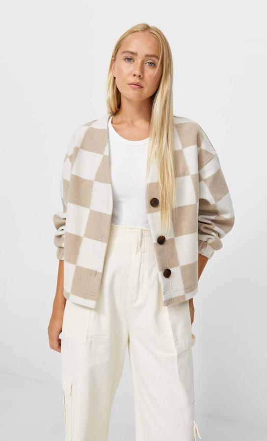 Estampado damero en tonos pastel para este cárdigan de punto con cuello caja y mangas largas que es de Stradivarius y tiene cierre frontal de botones a contraste. Cuesta 25,99 euros y está disponible en verde y crudo, en marrón y crudo o en cuadros grises entre las tallas XS y XL.