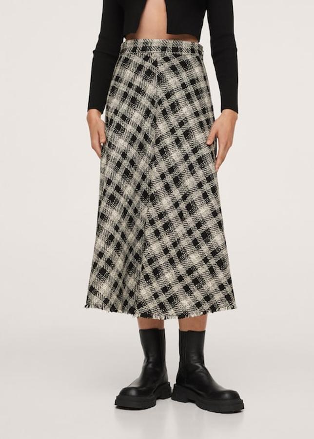 Con un bonito estampado de cuadros en tonos blancos y negros, esta falda de algodón de Mango confeccionada en tejido con textura viene con bajo deshilachado y es de diseño midi acampanado. De tiro alto, cuesta 39,99 euros y podemos encontrarla entre las tallas XS y XL. 