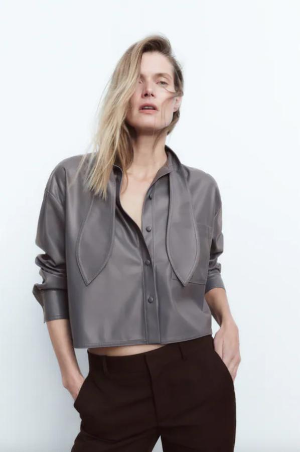 En color gris y con lazada en el cuello, esta camisa en efecto piel de Zara viene con mangas largas acabadas en puño, bolsillo de plastrón en delantero y bajo asimétrico. Podemos encontrarla entre las tallas XS y XL por 29,95 euros. 