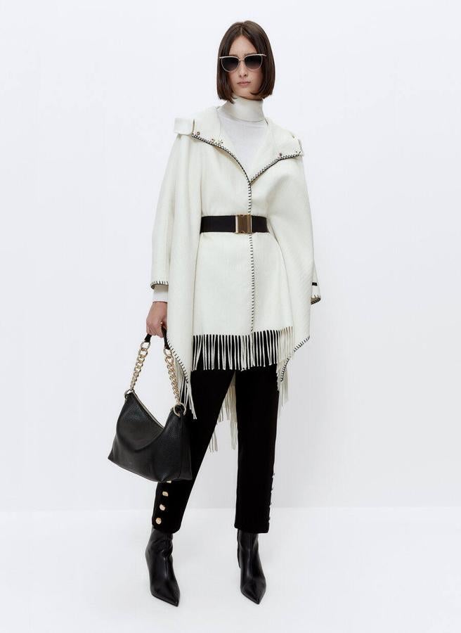 Capa de lana con capucha y flecos en crudo de Uterqüe. 229 euros