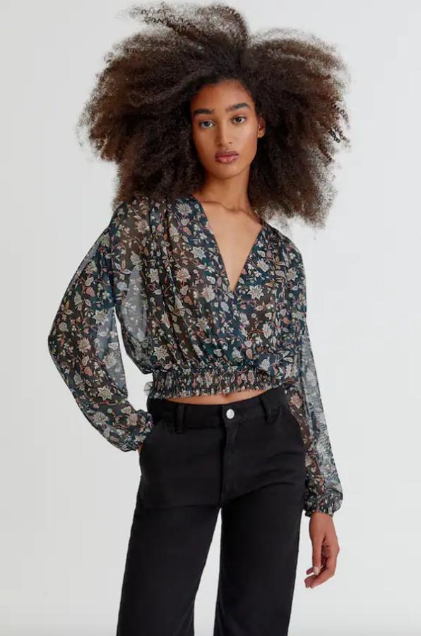 En tul, con estampado de flores en blanco y rosa sobre verde botella oscuro, esta blusa con cuello de pico cruzado y cintura elástica es de Pull&Bear y está disponible entre las tallas XS y XL por 17,99 euros. 
