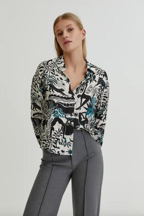 Estampado tropical en color negro y turquesa sobre fondo blanco para esta camisa de mangas largas y cuello de solapa de Pull&Bear que podemos encontrar entre las tallas XS y XL por 19,99 euros. 