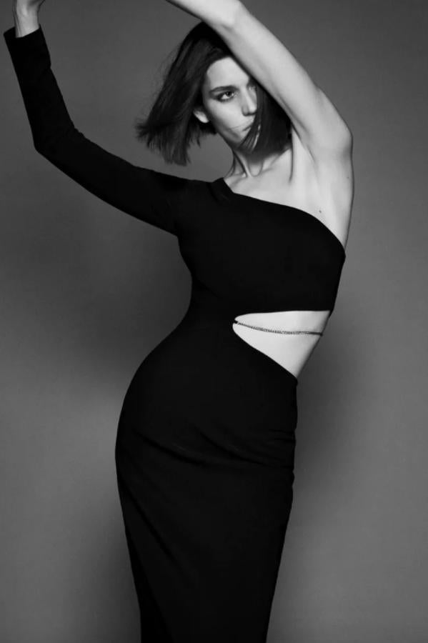 Este vestido negro de diseño midi está confeccionado en tejido elástico y viene con escote asimétrico, mangas largas y detalle de abertura con cadena en la cintura. Con bajo con abertura en la espalda, es de Zara, cuesta 39,95 euros y está disponible entre las tallas XS y XXL. 