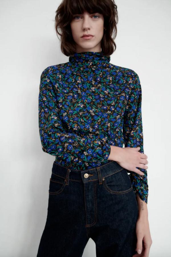 Cuello subido y mangas largas para esta camisa de fondo negro con estampado floral en verde y en azul. Con detalle de acabados con frunces elásticos y cierre lateral con cremallera oculta en costura, tiene un precio de 25,95 euros. 