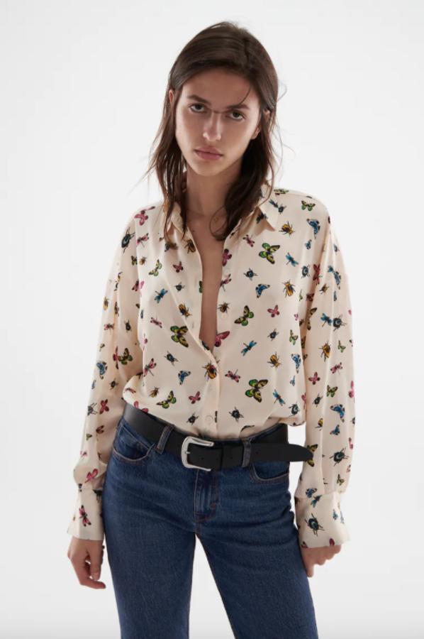 Estampado de mariposas multicolor sobre fondo crudo o verde agua para esta camisa satinada de cuello solapa con mangas largas y diseño amplio. Con bajo con aberturas laterales y cierre frontal de botones forrados tiene un precio de 22,95 euros. 