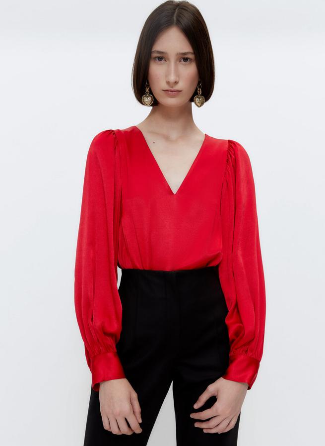 Mangas abullonadas y cuello de pico para esta camisa en rojo satinado confeccionada en tejido fluido de Uterqüe que cuesta 79 euros y está disponible en las tallas S, M y L. 