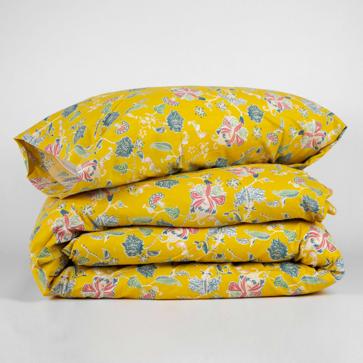 Imagen secundaria 1 - La colcha jacquard en chenilla de color mostaza cuesta 49.99 euros en Tramas+, el conjunto de funda nórdica con cojines, 26.99 euros, y las sábanas con estampado floral, 25.99 euros.