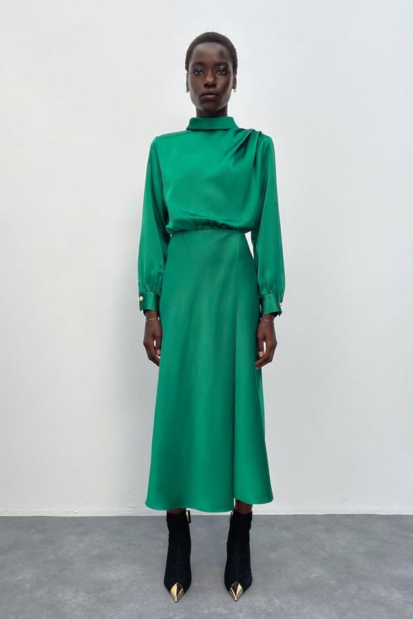 ¿Boda a la vista? Este vestido verde tiene todo lo que necesitas para triunfar en cualquier evento formal en pleno invierno. Satinado, con cuello alto y botones con perla. Vestido midi de Zara (39,99 euros)