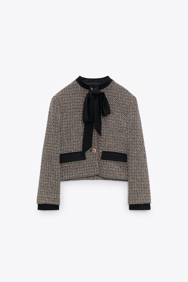 Una prenda a medio camino entre la chaqueta de  tweed  y la camisa con lazada. Chaqueta corta de Zara en blanco y negro de Zara (49,99 euros). 