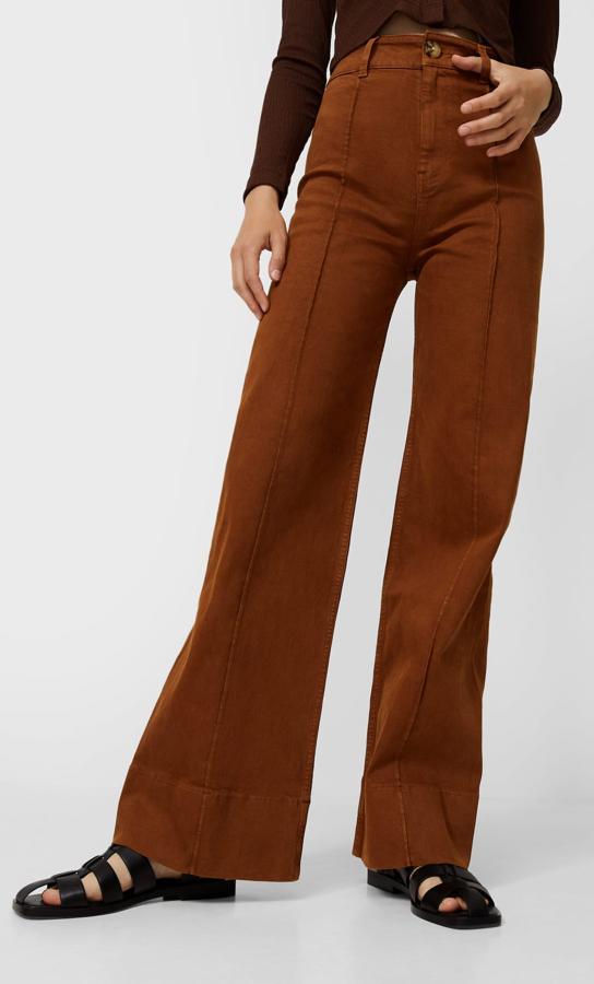 Diseño minimal con líneas marcadas en el frontal para estos pantalones marrones de pernera ancha y tiro alto con bajo ligeramente acampanado que cuestan 25,99 euros y están disponibles entre las tallas 32 y 44.