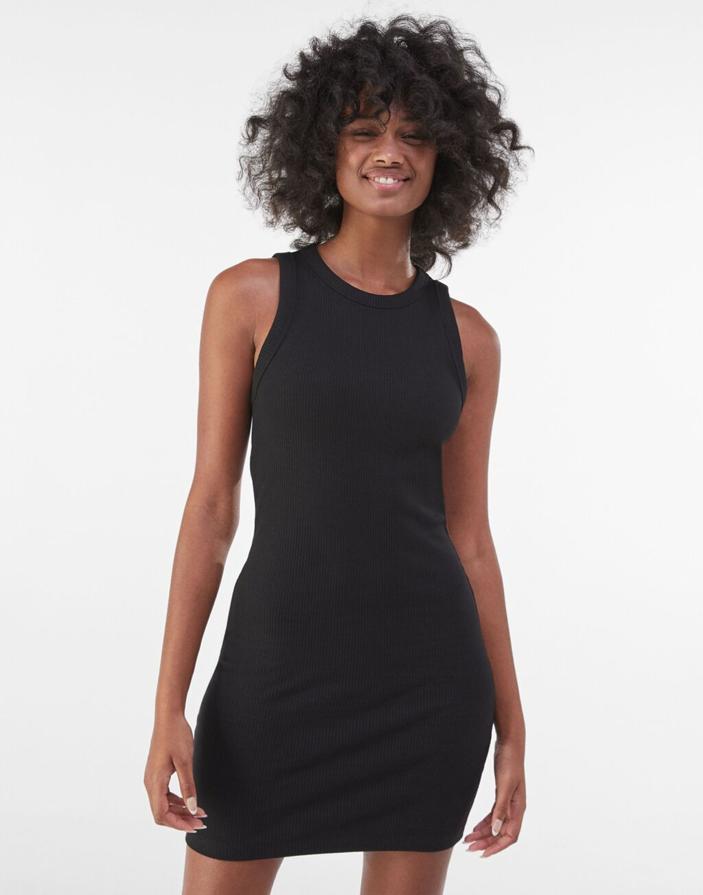 Cuello redondo y mangas sisa para este vestido corto negro en rib de Bershka que tiene un precio de 9,99 euros y podemos encontrar entre las tallas S y XL.