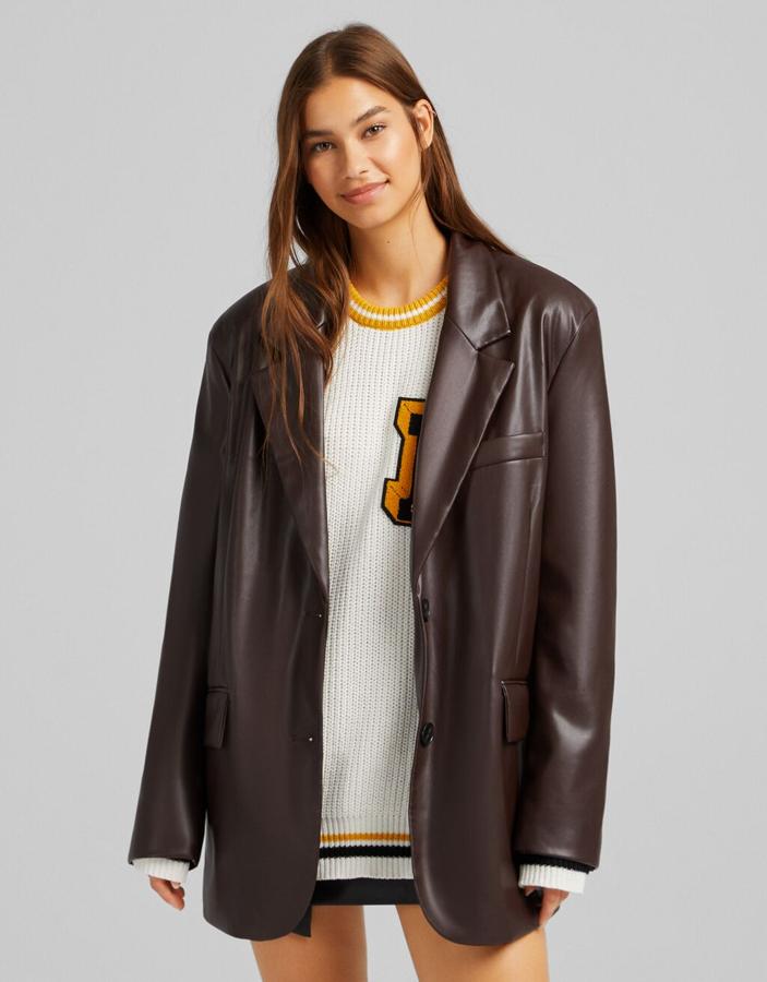 En Bershka han apostado por el marrón oscuro y el negro para esta blazer en efecto piel de diseño ligeramente oversize, con bolsillos de solapa laterales y bolsillo de vivo en el pecho que tiene abertura en el bajo en la espalda y cuesta 29,99 euros. 