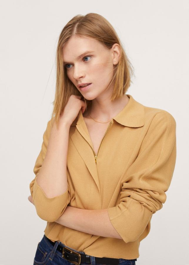 Este cárdigan confeccionado en punto fino y de diseño recto está disponible en negro o en ocre y viene con cuello polo, mangas largas y cierre de cremallera en la parte frontal oculto por tapeta. Podemos encontrarlo en las tallas S, M y L por 39,99 euros.