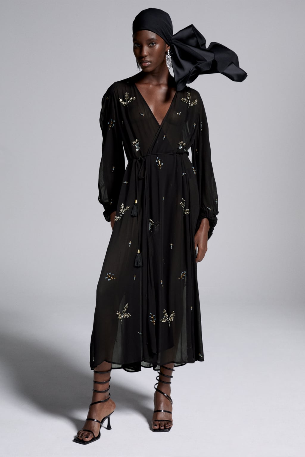 Aquí tenemos una prenda tan versátil para los días de fiesta que se puede llevar de dos maneras. Como vestido cruzado o abierto como chaqueta larga. Vestido negro de corte midi con bordados joya de Zara (79,99 euros). 