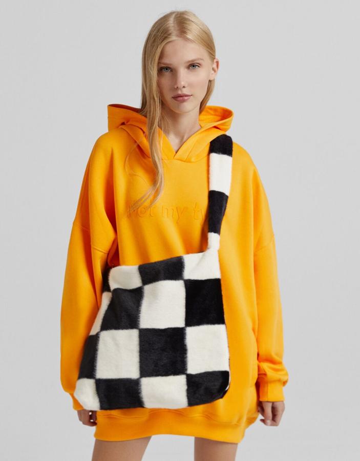 En efecto pelo y una única asa de hombro a tono, este bolso con estampado damero en blanco y negro de Bershka tiene un precio de 19,99 euros.