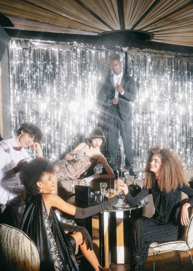 De izda. a dcha., total look blanco, de Prada. Vestido de Lanvin, guantes de Miscreants y pendientes de Swarovski. Vestido de Givenchy y guantes de Manokhi. Traje negro, camisa y zapatos, de Emidio Tucci en El Corte Inglés. Blusa y pantalón de Green Coast en El Corte Inglés; collar y pendientes, de El Corte Inglés y zapatos de Gloria Ortiz en El Corte Inglés. Bolsos sobre la mesa, de izda. a dcha.: Prada, Chanel, Celine y Gloria Ortiz en El Corte Inglés.