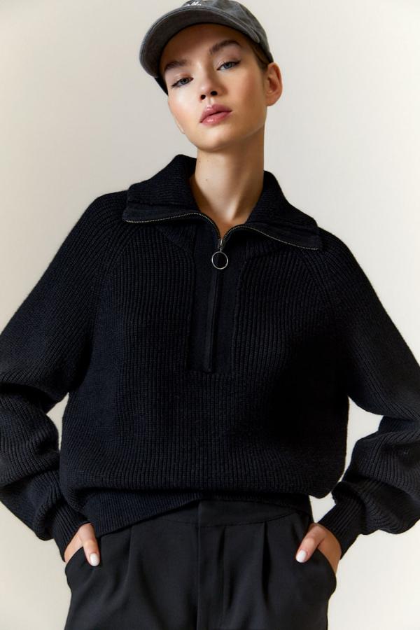 Disponible en negro, crudo y arena vigoré, este jersey de punto con cuello alto viene con cierre de cremallera con arandela y mangas largas. Cuesta 29,99 euros. 