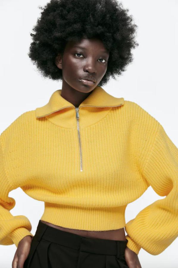 Diseño abullonado en las mangas largas acabadas en puño elástico para este jersey amarillo de Zara con cierre frontal tipo polo con cremallera metálica que podemos comprar por 29,95 euros.