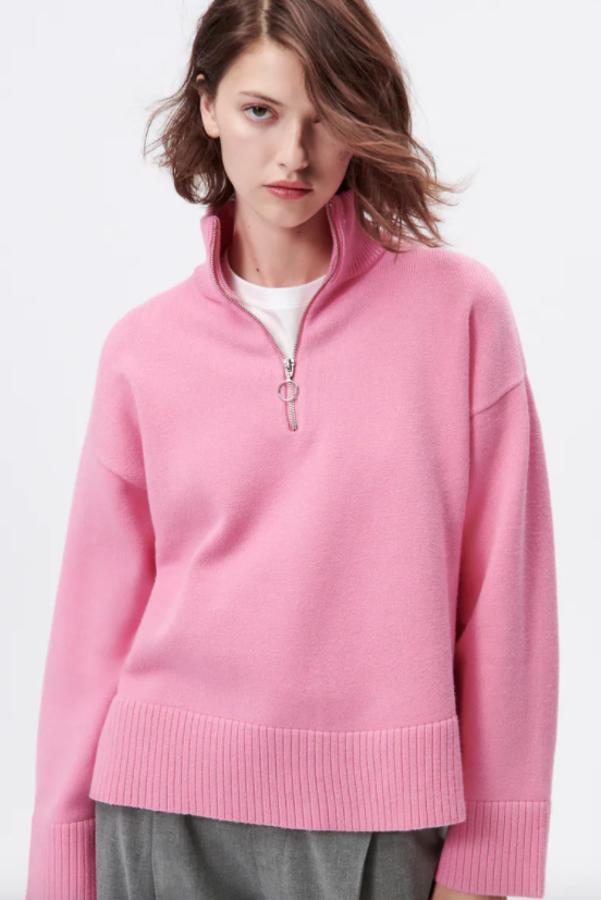 Con bajo asimétrico y acabados en rib, este jersey rosa de cuello subido y mangas largas que viene con cierre frontal de cremallera metálica en el escote es de Zara y cuesta 29,95 euros.