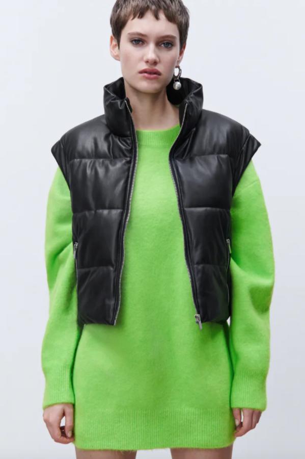 En diseño corto, efecto piel y color negro, este chaleco de cuello subido con manga sisa y hombros marcados viene con bolsillos delanteros con cremallera y cierre frontal de cremallera metálica. Cuesta 29,95 euros. 