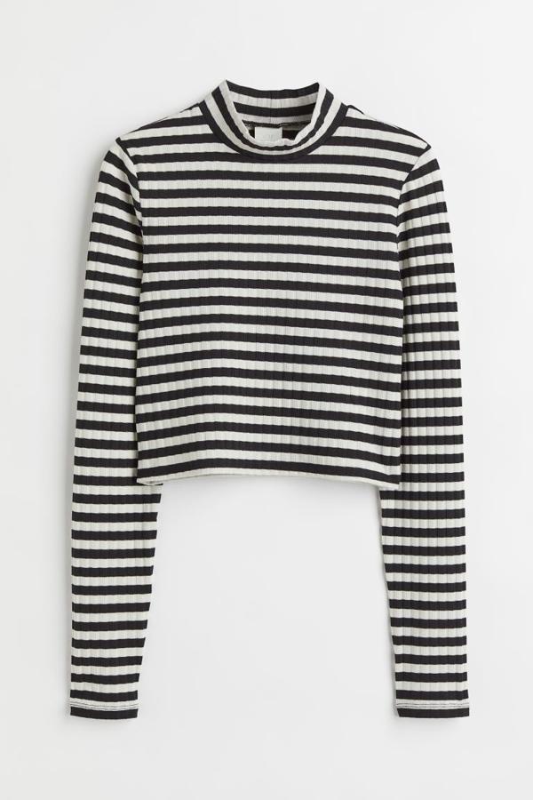 Estampado de rayas blancas y negras para este top cropped en punto de canalé, con cuello perkins y mangas largas, que tiene un precio de 9,99 euros. 