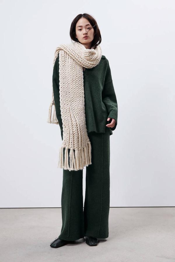 Zara nos trae el diseño más clásico: una bufanda de punto grueso acabada en flecos. Está disponible en color crudo y en negro. Puede ser tuya por 22,95 €.