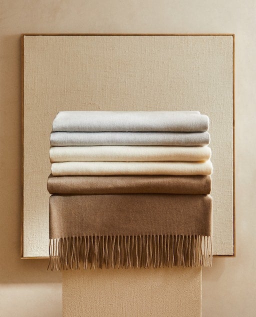 Loas notas de lujo con un punto sostenible se cuelan en nuestra casa a través de detalles premium como estas mantas de cashemire (199 euros en Zara Home).