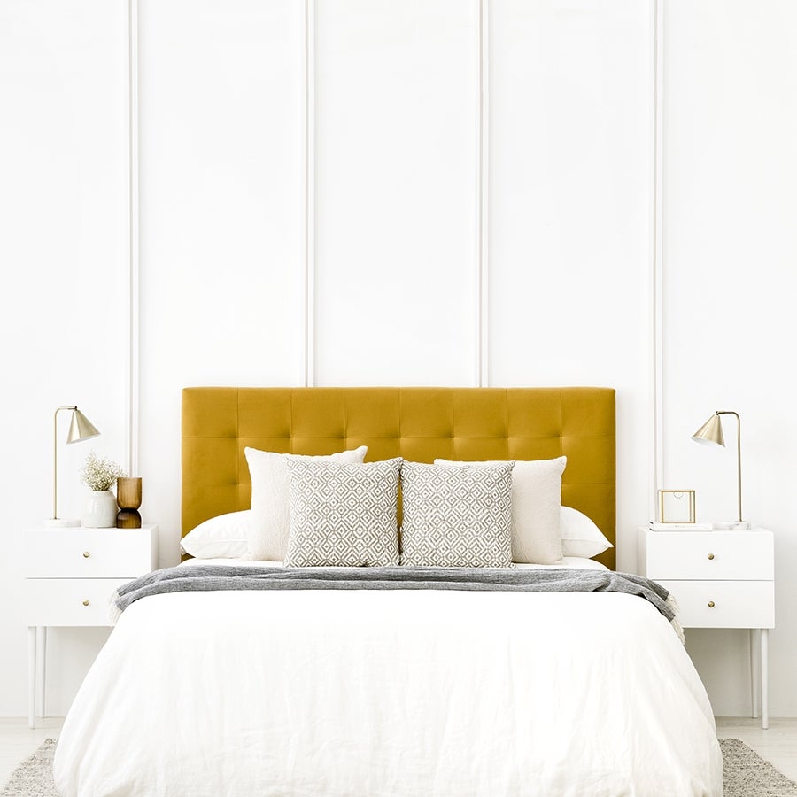 Este cabecero tapizado en terciopelo mostaza, ideal para poner una nota de color en el dormitorio siguiendo la regla 60-30-10, está rebajado de 281 a 149 euros en Kenay Home.