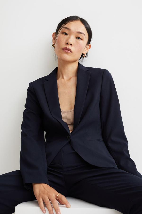 Diseño entallado para esta americana en azul marino que podemos encontrar en H&M. Viene con solapas de muesca y cierre frontal de un botón, bolsillos ribeteados y botones decorativos en los puños. Con abertura en la espalda, podemos comprarla por 29,99 euros. 