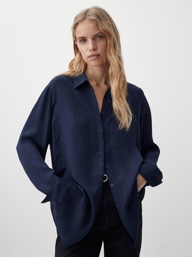 Confeccionada en tejido fluido, con cierre frontal de botones a tono oculto por tapeta y detalles con textura en el frontal, esta camisa en azul marino de Massimo Dutti con puños abotonados tiene un precio de 59,95 euros. 