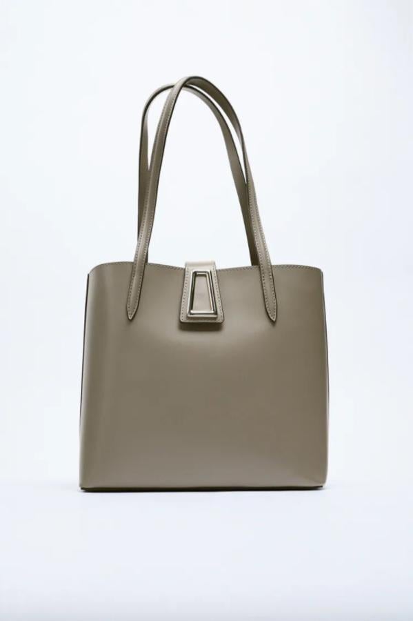 Este bolso en formato shopper de Zara que podemos encontrar en negro o en gris piedra viene con bolsillo interior con cierre de cremallera, doble asa de hombro y cierre de imán con detalle metálico. Costaba 29,95 euros y ahora está por 19,99 euros. 