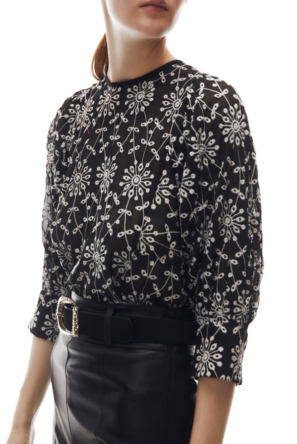 Bordados floreados en blanco sobre fondo negro para este top con escote en la espalda, con cuello redondo y mangas tres cuartos acabadas en puño que cuesta 25,99 euros. 