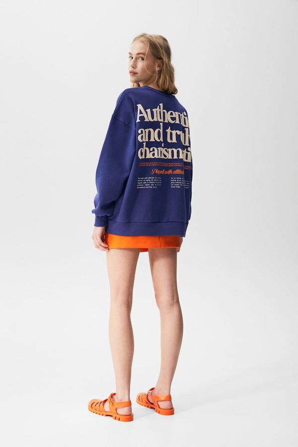 En azul eléctrico con gráfico en blanco y naranja o en naranja con gráfico en azul, esta sudadera de cuello redondo y y mangas largas es de Pull&Bear y cuesta 25,99 euros. 