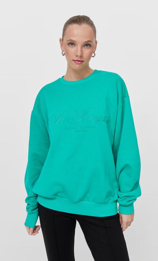 En verde aguamarina o en color tostado, esta sudadera de diseño oversize con cuello redondo y bordado a tono en el frontal es de Stradivarius y tiene un precio de 22,99 euros. 