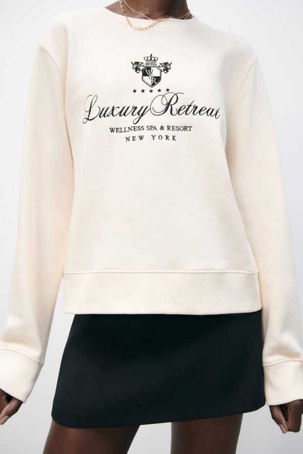 Esta bonita sudadera en blanco roto, con bordado a contraste en negro y cuello redondo con acabados en rib es de Zara y cuesta 22,95 euros.